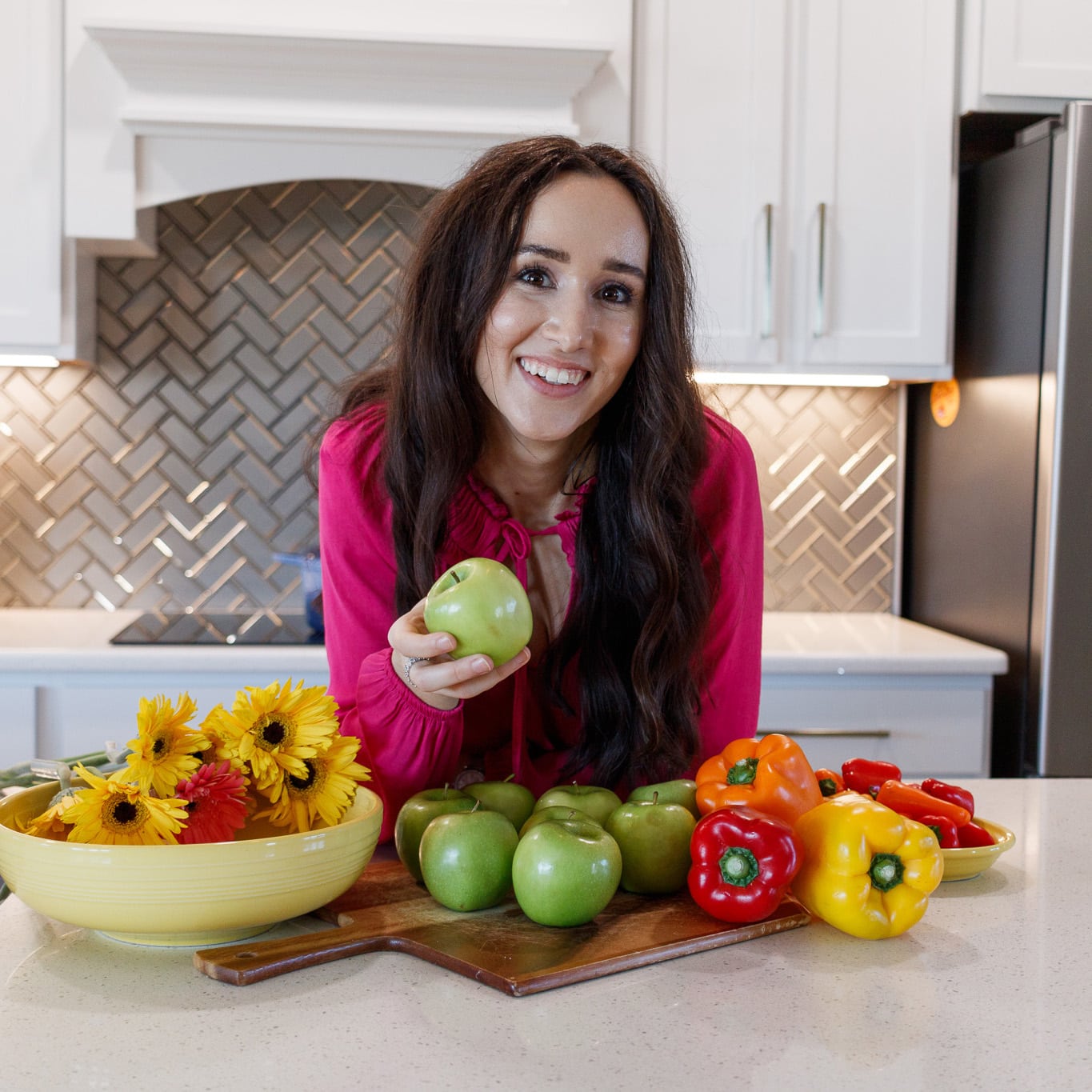 Dr. Chloe Skidmore holding an apple, surrounded by vibrant fresh produce, symbolizing the start of a healthful journey